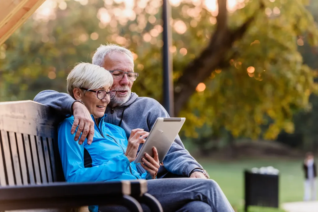 Senior couple reading tablet outdoors, RB Wealth retirement lifestyle planning Charlotte NC