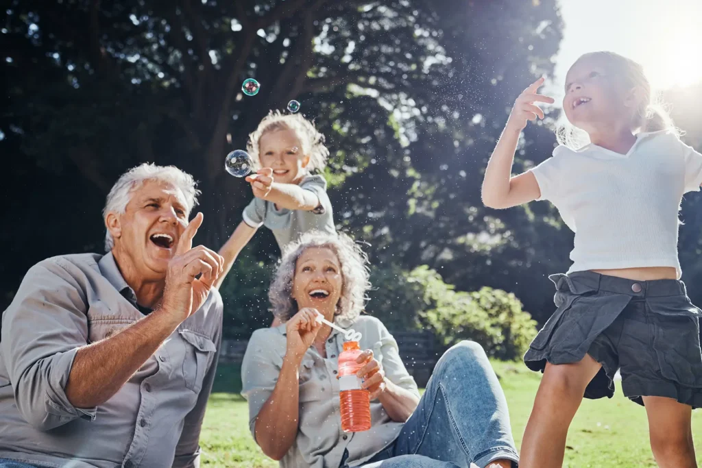 Grandparents playing with grandchildren in the park—carefree moments made possible by retirement income planning