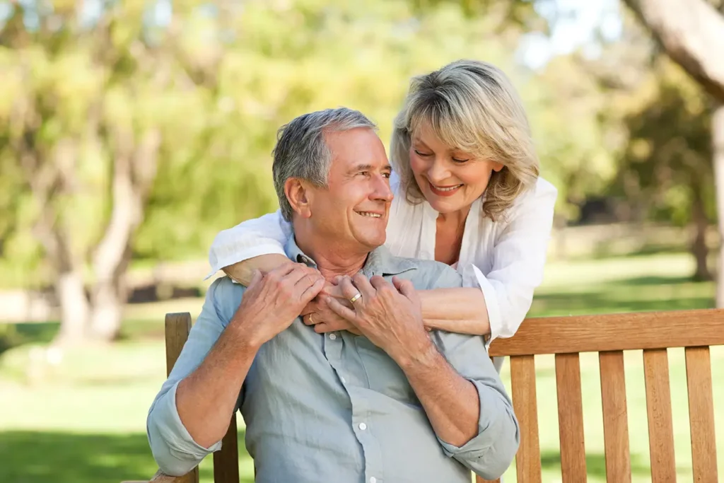 Smiling retired couple embracing on a park bench after successful retirement income planning